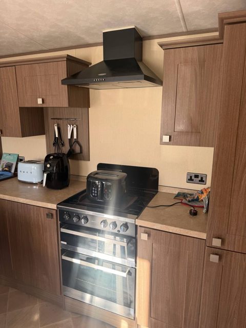 Caravan cooker wall with dark wood-effect units, before
